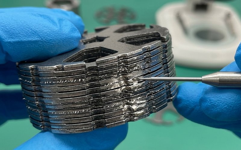 Technician inspecting the edge of a motor lamination stack where burrs and coating damage may cause interlaminar shorting