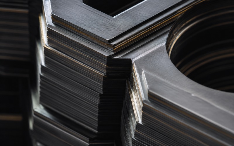 geometric macro view of hundreds of tightly stacked, razor-thin electrical steel motor laminations